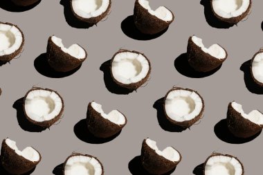 Gri bir arka planda çatlak bir hindistan cevizinin sert, güneşli, pürüzsüz deseni.