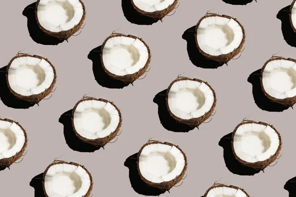 Gri bir arka planda çatlak bir hindistan cevizinin sert, güneşli, pürüzsüz deseni.