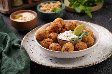 Geleneksel oryantal nohut bol yağda kızartılmış falafel tzatziki yoğurt sosu, humus taze limon ve siyah yüzeye yeşil kişniş.