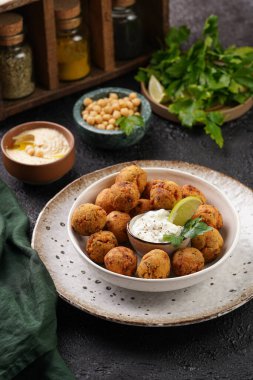 Geleneksel oryantal nohut bol yağda kızartılmış falafel tzatziki yoğurt sosu, humus taze limon ve siyah yüzeye yeşil kişniş.