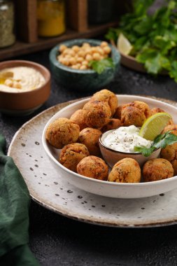 Geleneksel oryantal nohut bol yağda kızartılmış falafel tzatziki yoğurt sosu, humus taze limon ve siyah yüzeye yeşil kişniş.