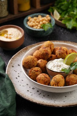 Geleneksel oryantal nohut bol yağda kızartılmış falafel tzatziki yoğurt sosu, humus taze limon ve siyah yüzeye yeşil kişniş.