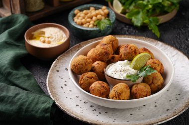 Geleneksel oryantal nohut bol yağda kızartılmış falafel tzatziki yoğurt sosu, humus taze limon ve siyah yüzeye yeşil kişniş.