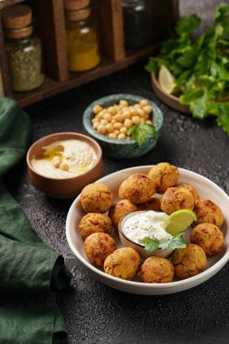 Geleneksel oryantal nohut bol yağda kızartılmış falafel tzatziki yoğurt sosu, humus taze limon ve siyah yüzeye yeşil kişniş.