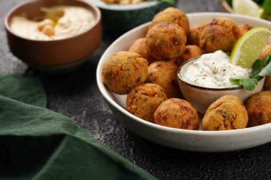 Geleneksel oryantal nohut bol yağda kızartılmış falafel tzatziki yoğurt sosu, humus taze limon ve siyah yüzeye yeşil kişniş.