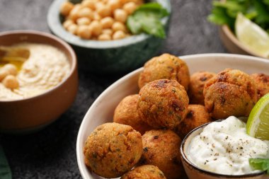 Geleneksel oryantal nohut bol yağda kızartılmış falafel tzatziki yoğurt sosu, humus taze limon ve siyah yüzeye yeşil kişniş.