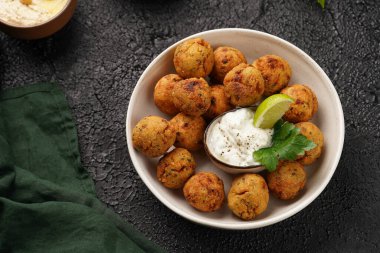 Geleneksel oryantal nohut bol yağda kızartılmış falafel tzatziki yoğurt sosu, humus taze limon ve siyah yüzeye yeşil kişniş.