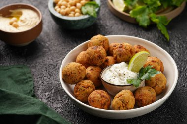 Geleneksel oryantal nohut bol yağda kızartılmış falafel tzatziki yoğurt sosu, humus taze limon ve siyah yüzeye yeşil kişniş.