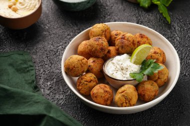 Geleneksel oryantal nohut bol yağda kızartılmış falafel tzatziki yoğurt sosu, humus taze limon ve siyah yüzeye yeşil kişniş.