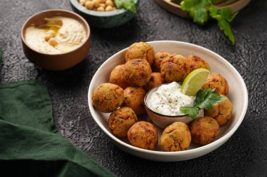 Geleneksel oryantal nohut bol yağda kızartılmış falafel tzatziki yoğurt sosu, humus taze limon ve siyah yüzeye yeşil kişniş.