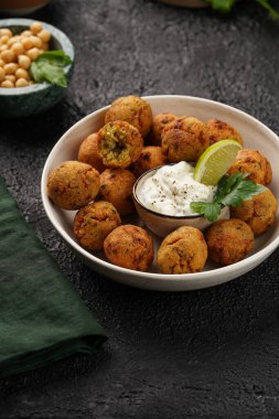Geleneksel oryantal nohut bol yağda kızartılmış falafel tzatziki yoğurt sosu, humus taze limon ve siyah yüzeye yeşil kişniş.