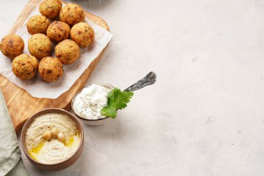 Geleneksel oryantal nohut, ahşap bir tahtada kızartılmış falafel, tzatziki yoğurt sosu, humus, taze kireç ve yeşil kişniş hafif yüzeyde, tet için kopyalama alanı