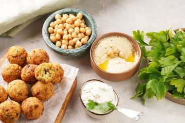 Geleneksel oryantal nohut, ahşap bir tahtada kızartılmış falafel, tzatziki yoğurt sosu, humus, taze limon ve yeşil kişniş.