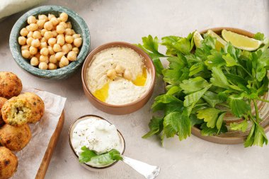 Geleneksel oryantal nohut, ahşap bir tahtada kızartılmış falafel, tzatziki yoğurt sosu, humus, taze limon ve yeşil kişniş.