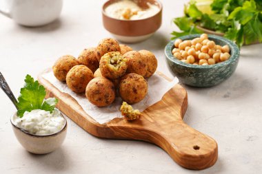 Geleneksel oryantal nohut, ahşap bir tahtada kızartılmış falafel, tzatziki yoğurt sosu, humus, taze limon ve yeşil kişniş.