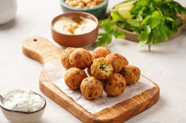 Geleneksel oryantal nohut, ahşap bir tahtada kızartılmış falafel, tzatziki yoğurt sosu, humus, taze limon ve yeşil kişniş.