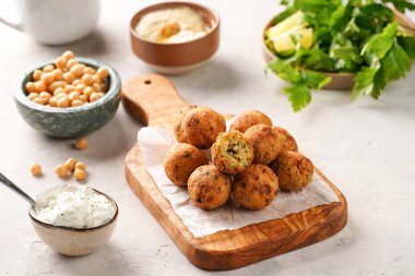 Geleneksel oryantal nohut, ahşap bir tahtada kızartılmış falafel, tzatziki yoğurt sosu, humus, taze limon ve yeşil kişniş.