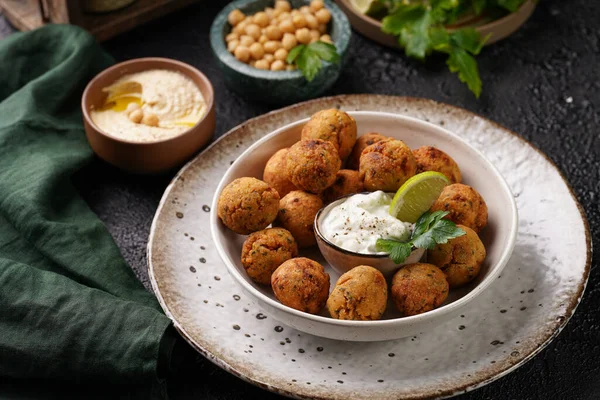 Geleneksel oryantal nohut bol yağda kızartılmış falafel tzatziki yoğurt sosu, humus taze limon ve siyah yüzeye yeşil kişniş.