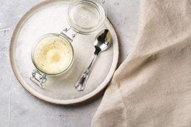 Mason jar with tasty herb butter with grated truffles on scandi plate on grey concrete surface, top view