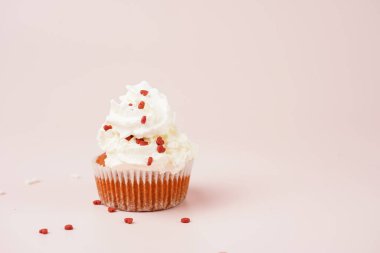 Beyaz kremalı ev yapımı çikolatalı kek ve pembe yüzeydeki mermer tahtada kalp paylaşımı kırmızı ve beyaz şeker süslemesi.