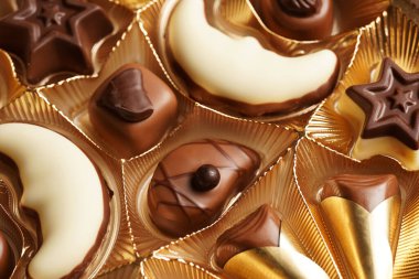 Altın renkli bir kutu sütlü ve koyu çikolatalı şeker, yakın plan, seçici odaklı.