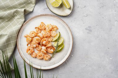 Limon, sarımsak ve taze otlarla servis edilen ızgara karides veya kaplan karidesleri. Beton yüzeyde Scandi yuvarlak tabağında. Peskataryan protein besin değeri