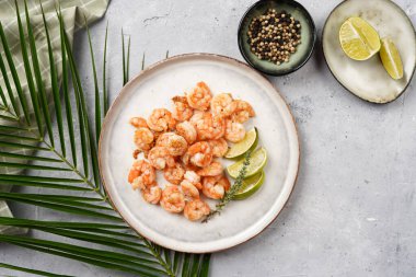 Limon, sarımsak ve taze otlarla servis edilen ızgara karides veya kaplan karidesleri. Beton yüzeyde Scandi yuvarlak tabağında. Peskataryan protein besin değeri