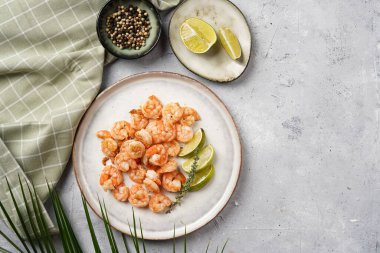 Limon, sarımsak ve taze otlarla servis edilen ızgara karides veya kaplan karidesleri. Beton yüzeyde Scandi yuvarlak tabağında. Peskataryan protein besin değeri