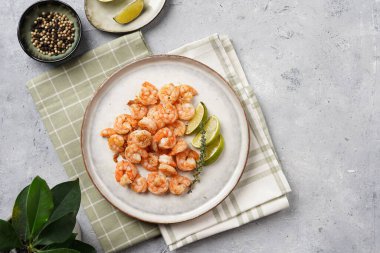 Limon, sarımsak ve taze otlarla servis edilen ızgara karides veya kaplan karidesleri. Beton yüzeyde Scandi yuvarlak tabağında. Peskataryan protein besin değeri