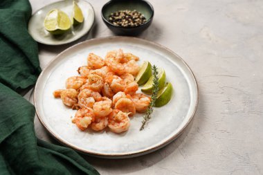 Limon, sarımsak ve taze otlarla servis edilen ızgara karides veya kaplan karidesleri. Beton yüzeyde Scandi yuvarlak tabağında. Peskataryan protein besin değeri