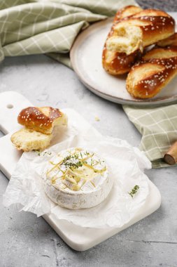 Fırında peynirli camembert peyniri, mermer tahtada sodyum somon ekmeği, gri beton yüzey. Yeşil kareli mutfak havlusunda kekik ile ev yapımı peynir.