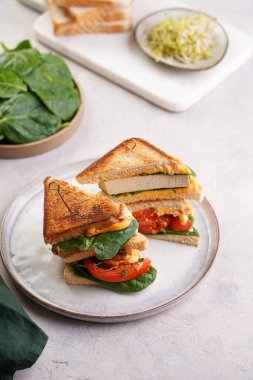 Amerikan yapımı, tofu, çedar peynirli, domates dilimli ve üçgen şeklinde kesilmiş beyaz tarama tabağında ıspanaklı ev yapımı peynirli sandviç. İtalyan Tramezzini