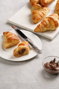 Bir tabak tereyağlı kruvasan ikiye bölünmüş ve mermer tepside fındık ezmeli yeni pişmiş Fransız dürümü.