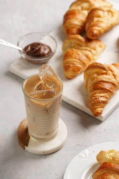 Sklenice Mléčnou Kávou Kostkami Ledu Čerstvě Upečené Croissanty Mramorové Desce — Stock fotografie