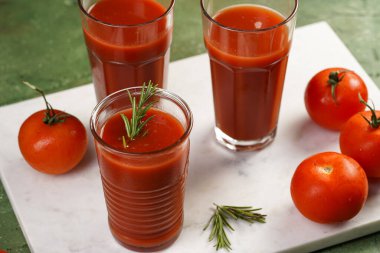 Kırmızı alkolsüz domates suyuyla dolu birkaç bardak yeşil arka planda mermer tabakta.