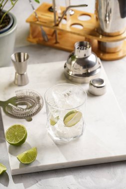 Buz küplü bir bardak, mermer tahtada limon ve ferahlatıcı içecek, titretici ve barmen ekipmanı