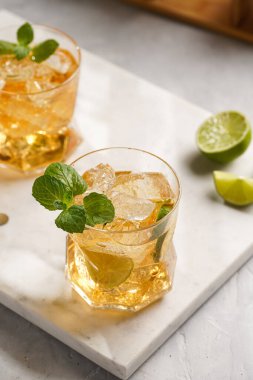 İçinde buz küpleri, limon ve ferahlatıcı portakal suyu olan bir bardak mermer tahtada nane, karıştırıcı ve barmen teçhizatı