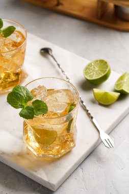 İçinde buz küpleri, limon ve ferahlatıcı portakal suyu olan bir bardak mermer tahtada nane, karıştırıcı ve barmen teçhizatı