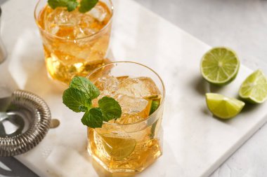 İçinde buz küpleri, limon ve ferahlatıcı portakal suyu olan bir bardak mermer tahtada nane, karıştırıcı ve barmen teçhizatı