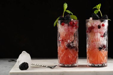 İki uzun bardak ve klasik böğürtlen ve mermer tahtada cin kokteylinin alkolsüz moktail versiyonu