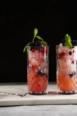 İki uzun bardak ve klasik böğürtlen ve mermer tahtada cin kokteylinin alkolsüz moktail versiyonu