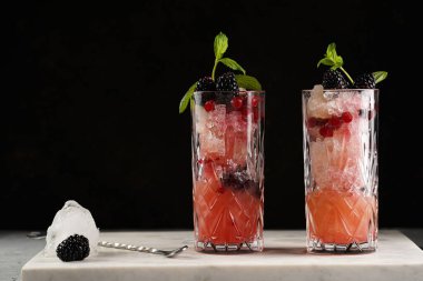 İki uzun bardak ve klasik böğürtlen ve mermer tahtada cin kokteylinin alkolsüz moktail versiyonu