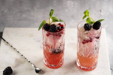 İki uzun bardak ve klasik böğürtlen ve mermer tahtada cin kokteylinin alkolsüz moktail versiyonu