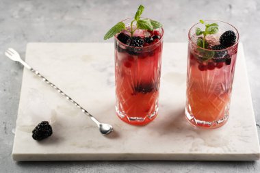 İki uzun bardak ve klasik böğürtlen ve mermer tahtada cin kokteylinin alkolsüz moktail versiyonu