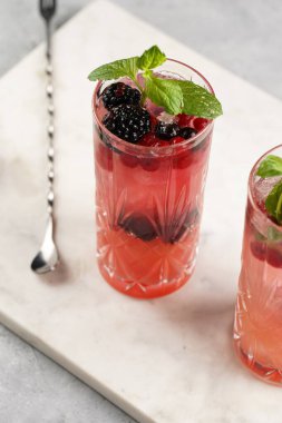 İki uzun bardak ve klasik böğürtlen ve mermer tahtada cin kokteylinin alkolsüz moktail versiyonu
