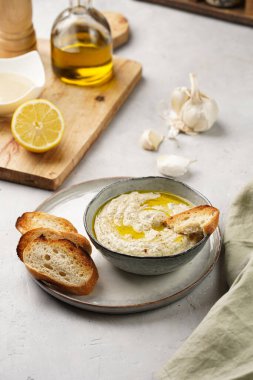 Geleneksel Arap mutfağı, patlıcan, tahin, kişniş, sarımsak, zeytin yağı, kızarmış baget ekmekli limon suyu ve gri arka planda kızarmış ekmek.