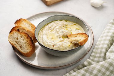 Geleneksel Arap mutfağı, patlıcan, tahin, kişniş, sarımsak, zeytin yağı, kızarmış baget ekmekli limon suyu ve gri arka planda kızarmış ekmek.