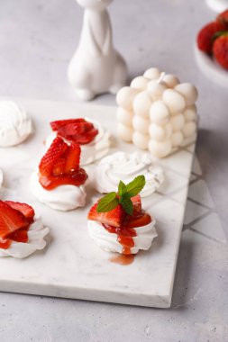 Mini-pavlova taze çilek ve kırmızı reçelli - mermer tahtada lezzetli kremalı pastalar, baloncuk mumu