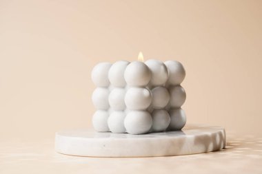 Bir gri baloncuk mum mermer tepside bej renkli dikişsiz yüzeyde yıldızlı ışık gölgeleriyle