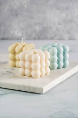 Üç baloncuk mum - soluk mavi yüzey üzerinde bej renkli ve mavi renkli - mermer tahta üzerinde